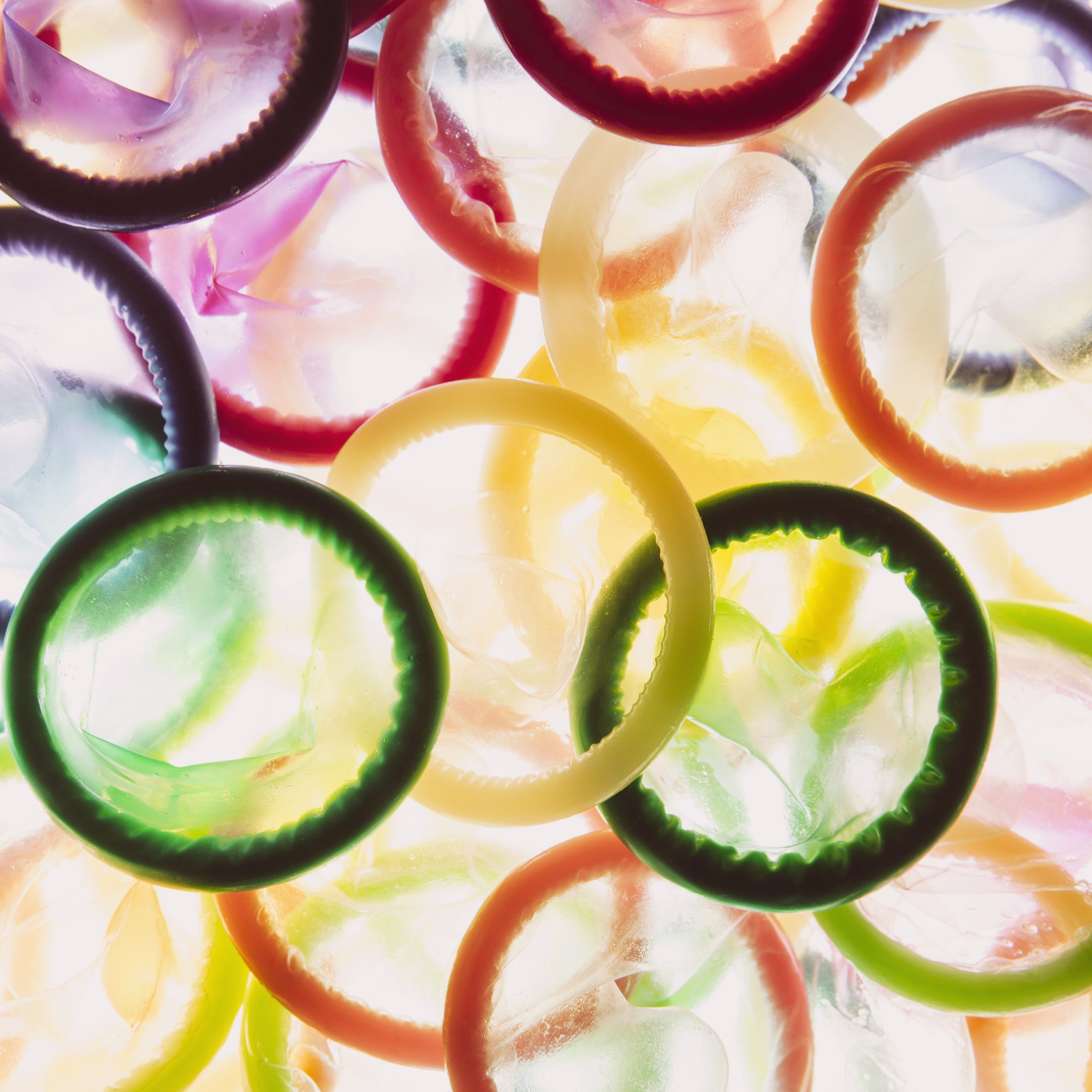 Large grouping of multi-colored condoms on white background,USA,A large group of multi-colored condoms displayed on a white background. Heaped up.